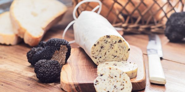 Homemade aromatic butter with black truffles on wooden board.Selective focus.